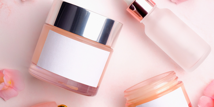 Элегантные косметические баночки и флакончик сыворотки с минималистичными этикетками на розовом фоне