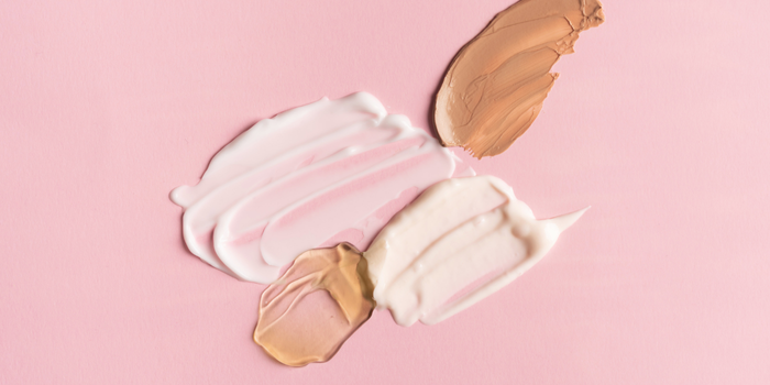 Образцы чистых косметических кремов и тональных средств на розовом фоне