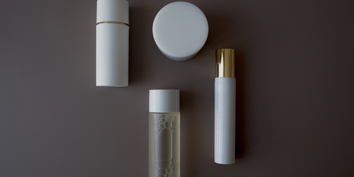 Минималистичные белые косметические контейнеры, расставленные на темном фоне.